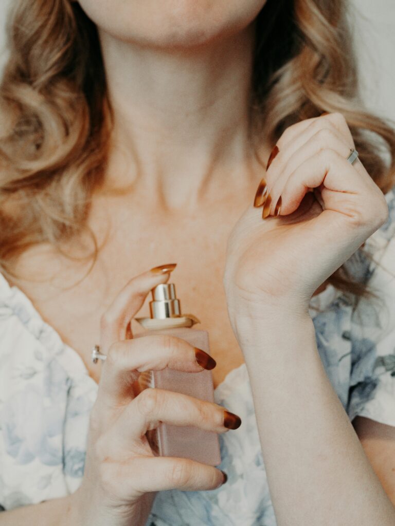Close-up of a woman spraying perfume on her wrist, showcasing elegance and femininity.