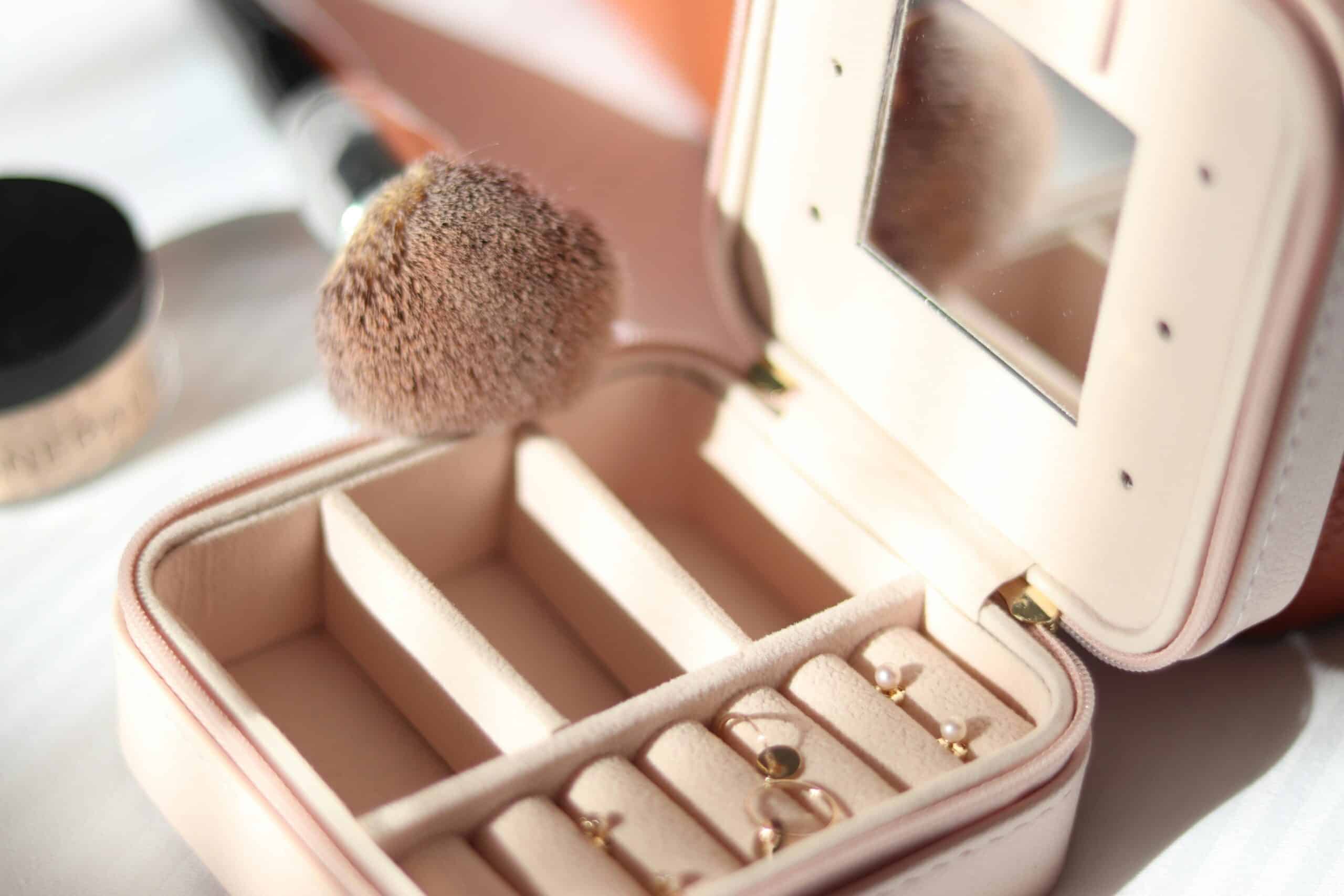 A luxurious jewelry box with earrings and a makeup brush bathed in gentle sunlight.